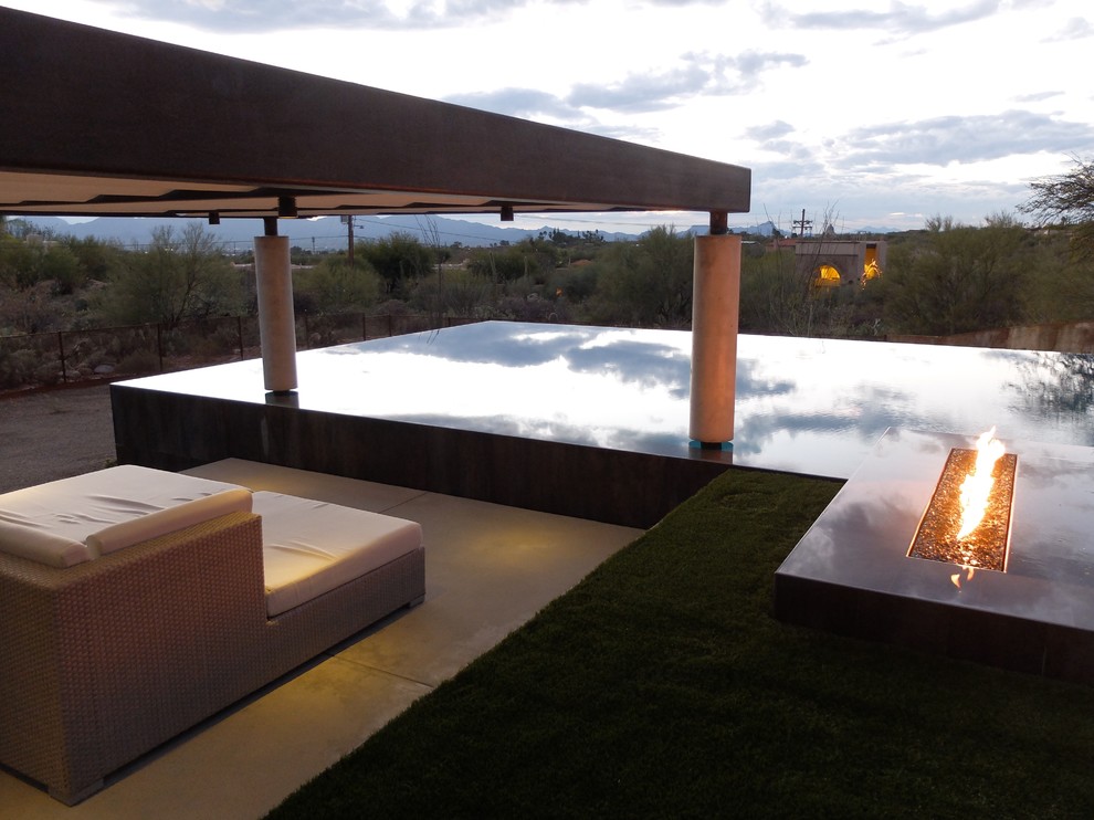 This is an example of a large contemporary backyard rectangular infinity pool in Phoenix with a hot tub and concrete pavers.