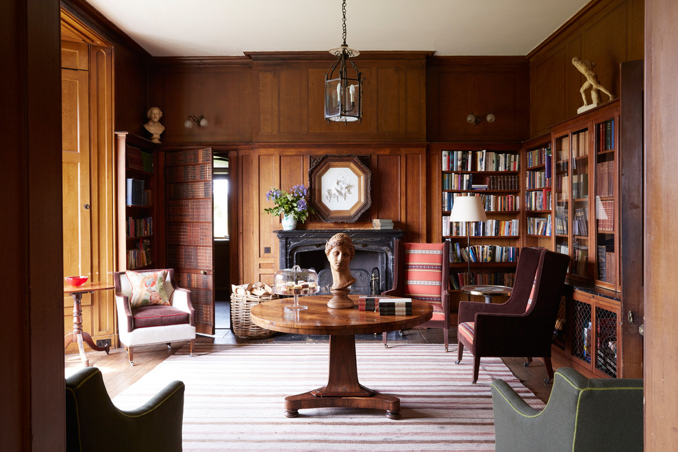 This is an example of a mid-sized traditional home office in London with a library, brown walls, light hardwood floors and brown floor.