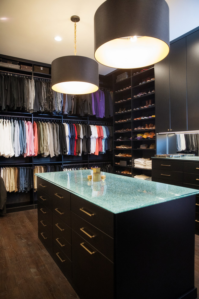 This is an example of a contemporary gender-neutral walk-in wardrobe in New Orleans with flat-panel cabinets, black cabinets, dark hardwood floors and brown floor.