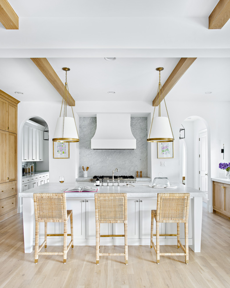 Inspiration for a large transitional l-shaped light wood floor, brown floor and exposed beam open concept kitchen remodel in Dallas with an undermount sink, shaker cabinets, white cabinets, marble countertops, white backsplash, marble backsplash, paneled appliances, an island and white countertops