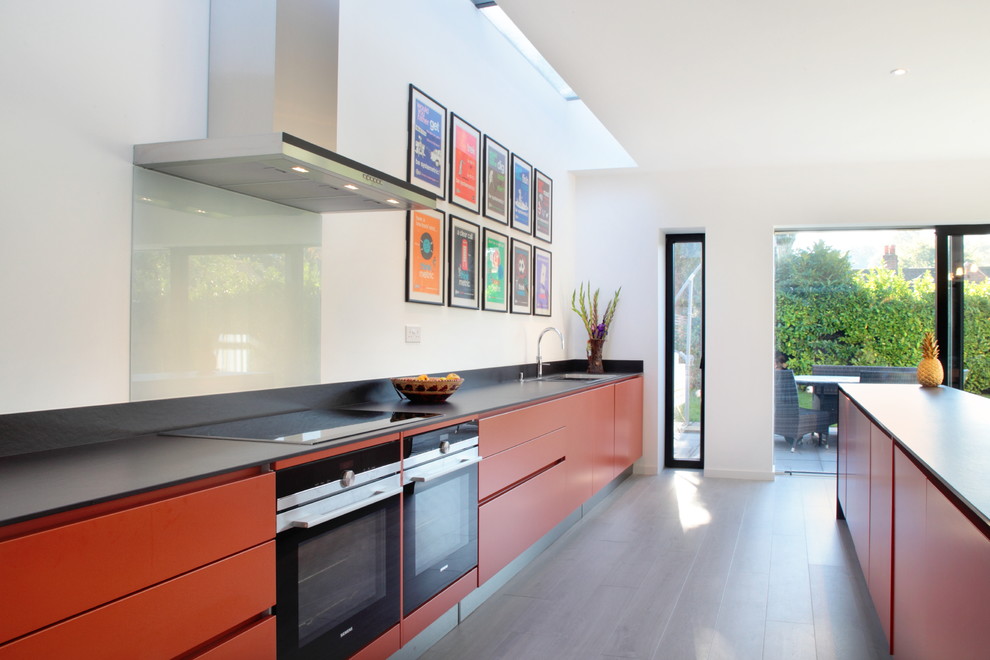Inspiration for a large contemporary galley open plan kitchen in Hertfordshire with orange cabinets, blue splashback, glass sheet splashback, stainless steel appliances, flat-panel cabinets, a drop-in sink, quartzite benchtops, dark hardwood floors and with island.