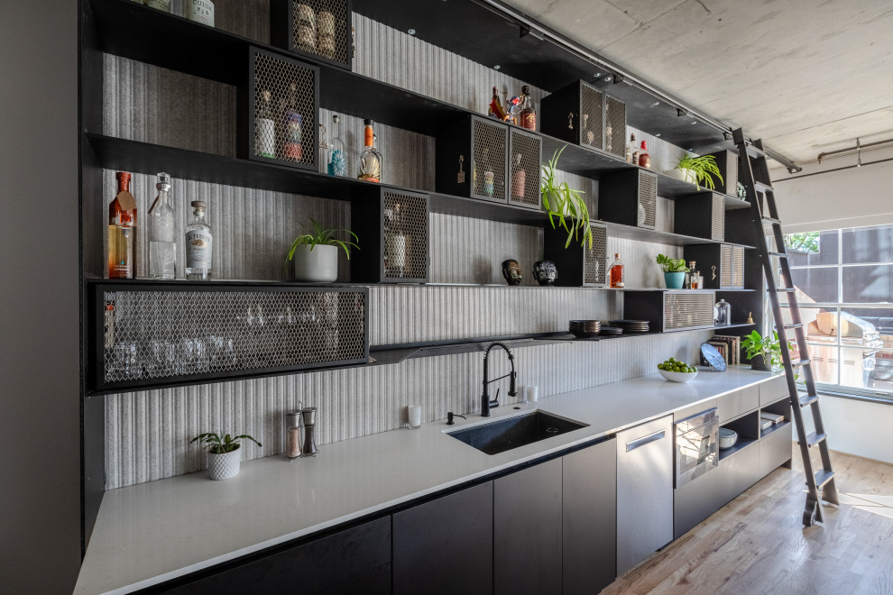 Foto di una cucina abitabile industriale con ante lisce, ante nere, pavimento marrone e top bianco