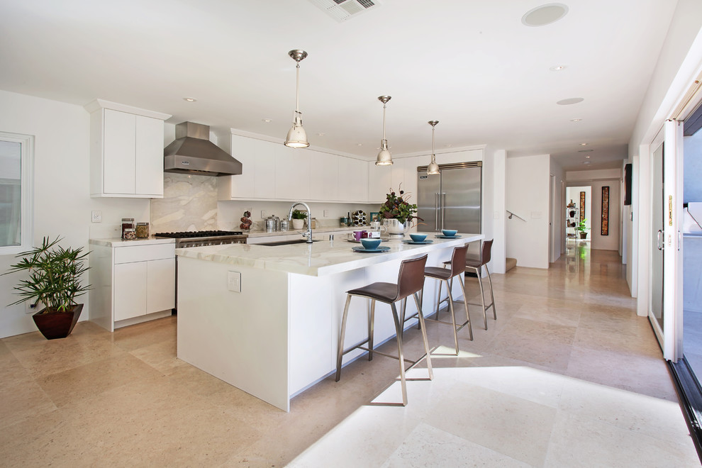 Beach style l-shaped kitchen in Orange County with an undermount sink, flat-panel cabinets, white cabinets, beige splashback and stainless steel appliances.