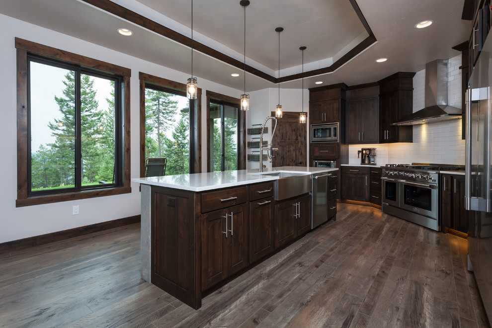 Inspiration for a rustic kitchen remodel with a farmhouse sink, white backsplash, ceramic backsplash, stainless steel appliances and an island