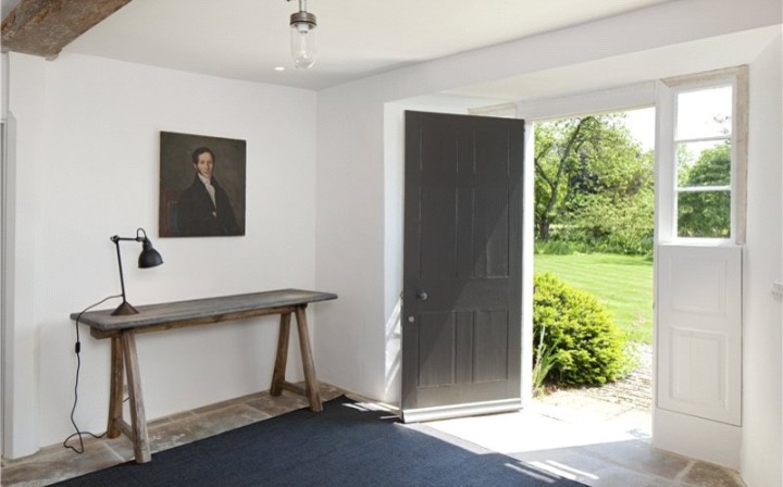 Photo of a large country entry hall in London with white walls, a single front door, a gray front door and limestone floors.