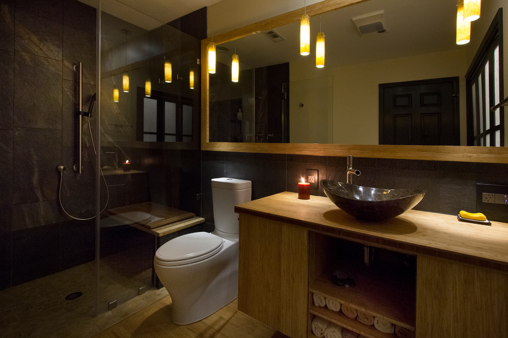 This is an example of a mid-sized contemporary master bathroom in Raleigh with a vessel sink, light wood cabinets, wood benchtops, a curbless shower, a two-piece toilet, porcelain tile, yellow walls, bamboo floors, flat-panel cabinets, black tile, yellow benchtops, yellow floor and a hinged shower door.