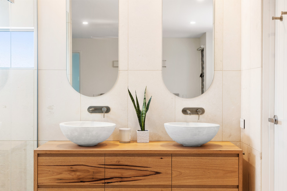Mid-sized beach style master limestone tile limestone floor and double-sink toilet room photo in Sunshine Coast with light wood cabinets and a floating vanity