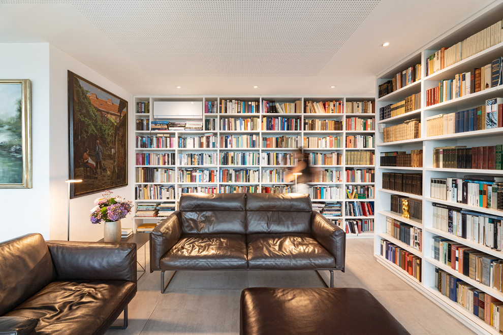 Esempio di un piccolo soggiorno contemporaneo aperto con libreria, pareti bianche, pavimento con piastrelle in ceramica, TV nascosta, pavimento grigio e carta da parati