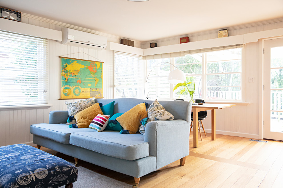 Modelo de sala de estar abierta retro grande con paredes blancas, suelo de madera clara, suelo marrón y machihembrado