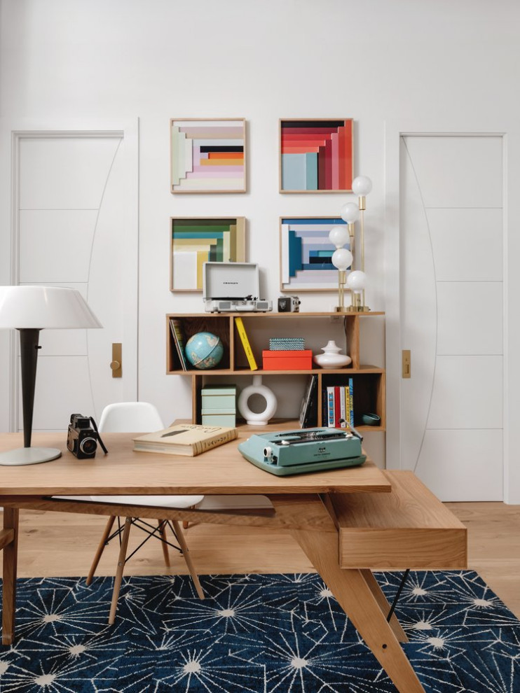 Medium sized midcentury home studio in Austin with white walls, medium hardwood flooring, no fireplace and a freestanding desk.