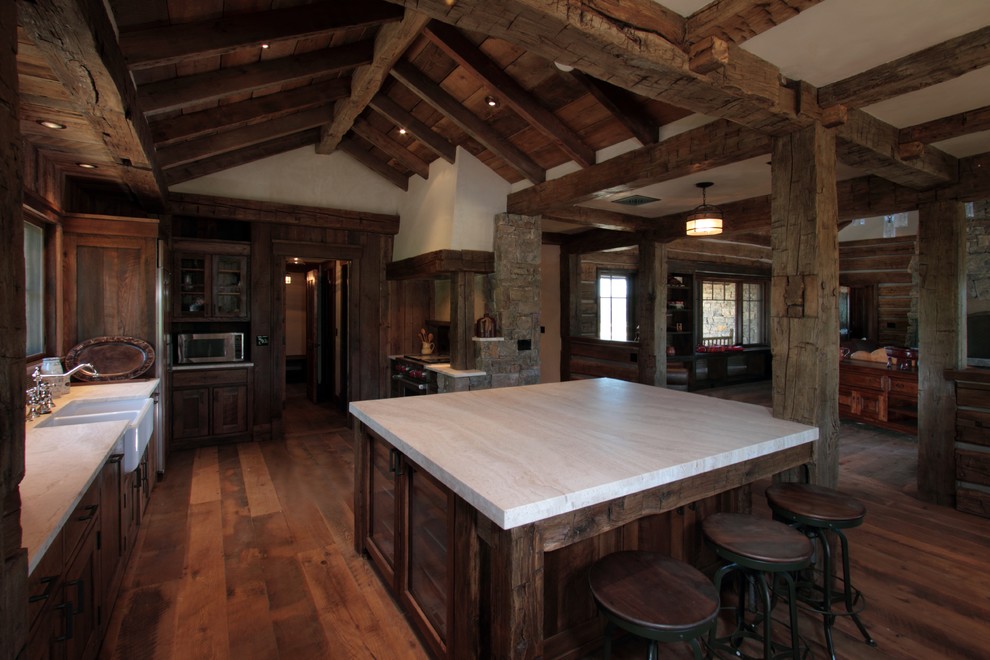 Photo of a large country open plan kitchen in Other with a farmhouse sink, dark wood cabinets, quartzite benchtops, stainless steel appliances, dark hardwood floors, with island and brown floor.