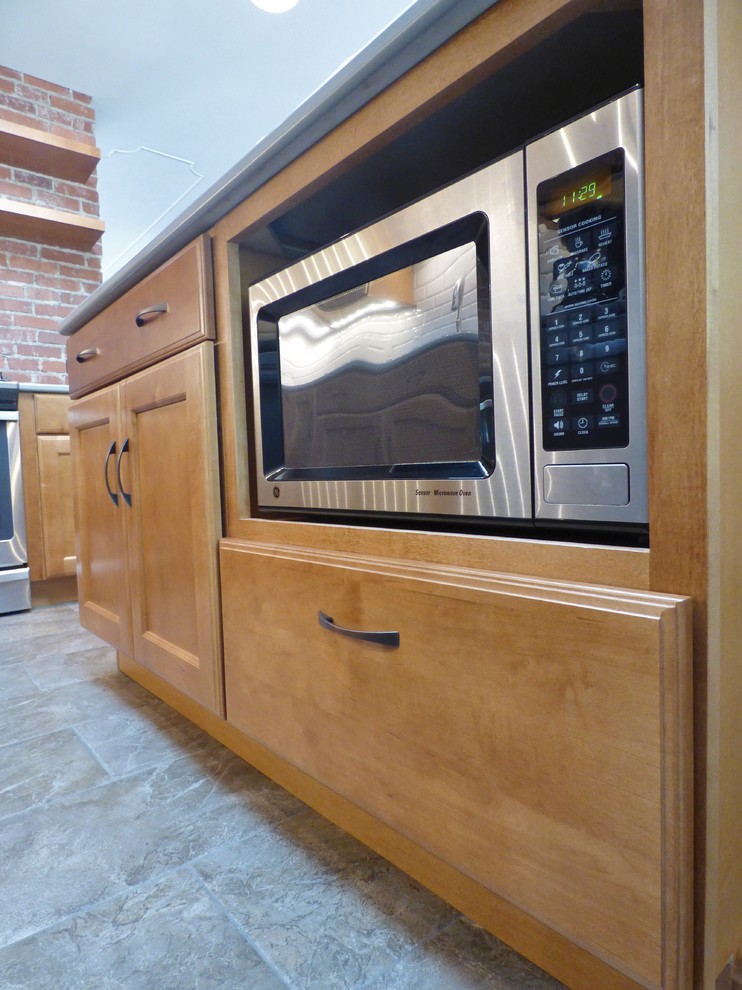Transitional l-shaped porcelain tile eat-in kitchen photo with an undermount sink, recessed-panel cabinets, medium tone wood cabinets, quartz countertops, white backsplash, subway tile backsplash, stainless steel appliances and an island