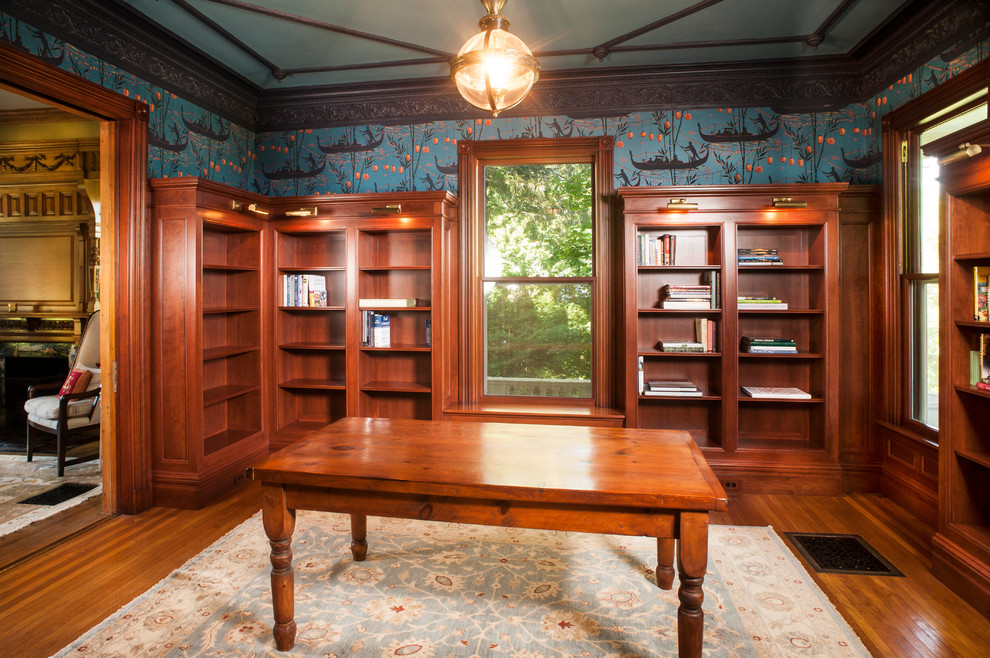 Design ideas for a mid-sized traditional home office in Portland Maine with a library, blue walls, medium hardwood floors, no fireplace, a freestanding desk and brown floor.