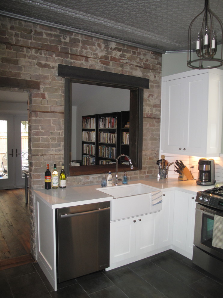 Enclosed kitchen - small transitional u-shaped porcelain tile enclosed kitchen idea in Toronto with a farmhouse sink, shaker cabinets, white cabinets, quartz countertops, white backsplash, porcelain backsplash, stainless steel appliances and no island