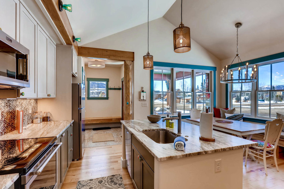 Inspiration for a small transitional single-wall light wood floor and brown floor open concept kitchen remodel in Denver with an undermount sink, shaker cabinets, gray cabinets, quartz countertops, blue backsplash, mosaic tile backsplash, stainless steel appliances, an island and gray countertops