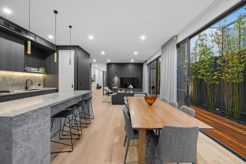 Idee per una sala da pranzo aperta verso il soggiorno design di medie dimensioni con pareti nere, parquet chiaro e boiserie