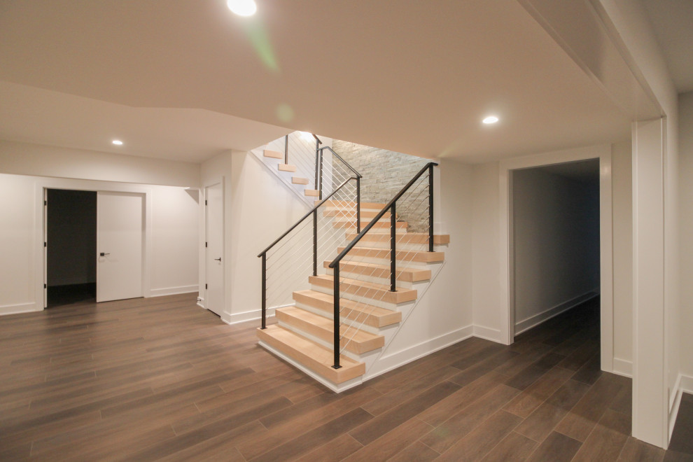 This is an example of a large eclectic wood floating staircase in DC Metro with metal railing and brick walls.