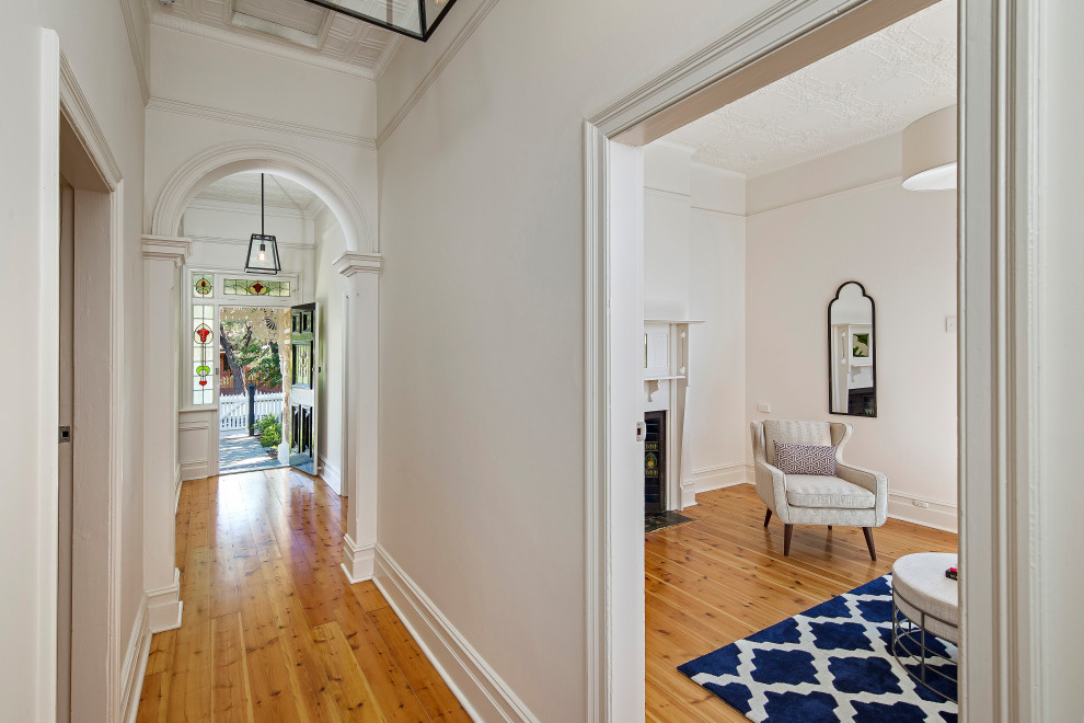 Photo of a large victorian entry hall in Adelaide with white walls, light hardwood floors, a single front door and a black front door.