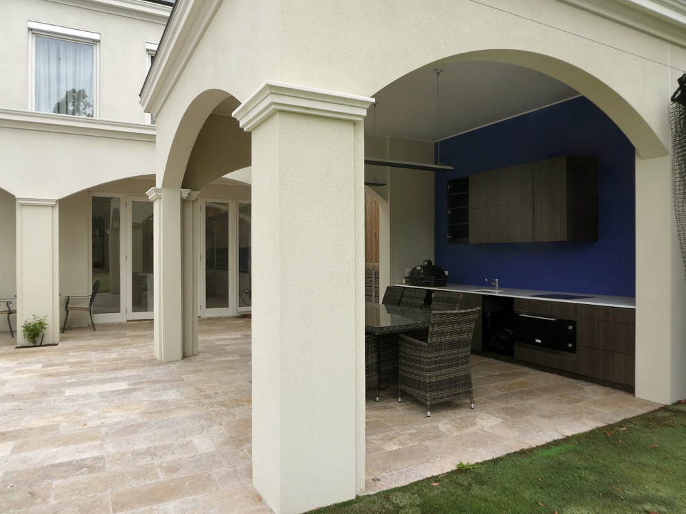 Photo of a large transitional backyard patio in Melbourne with an outdoor kitchen, natural stone pavers and a roof extension.