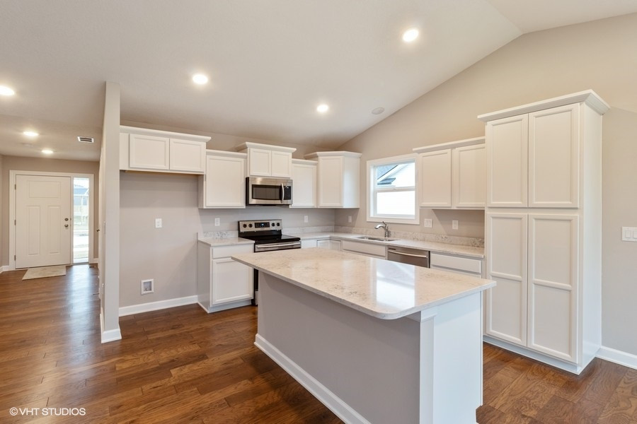 Kitchen - mid-sized transitional single-wall medium tone wood floor and brown floor kitchen idea with an undermount sink, shaker cabinets, white cabinets, quartz countertops, white backsplash, quartz backsplash, stainless steel appliances, an island and white countertops