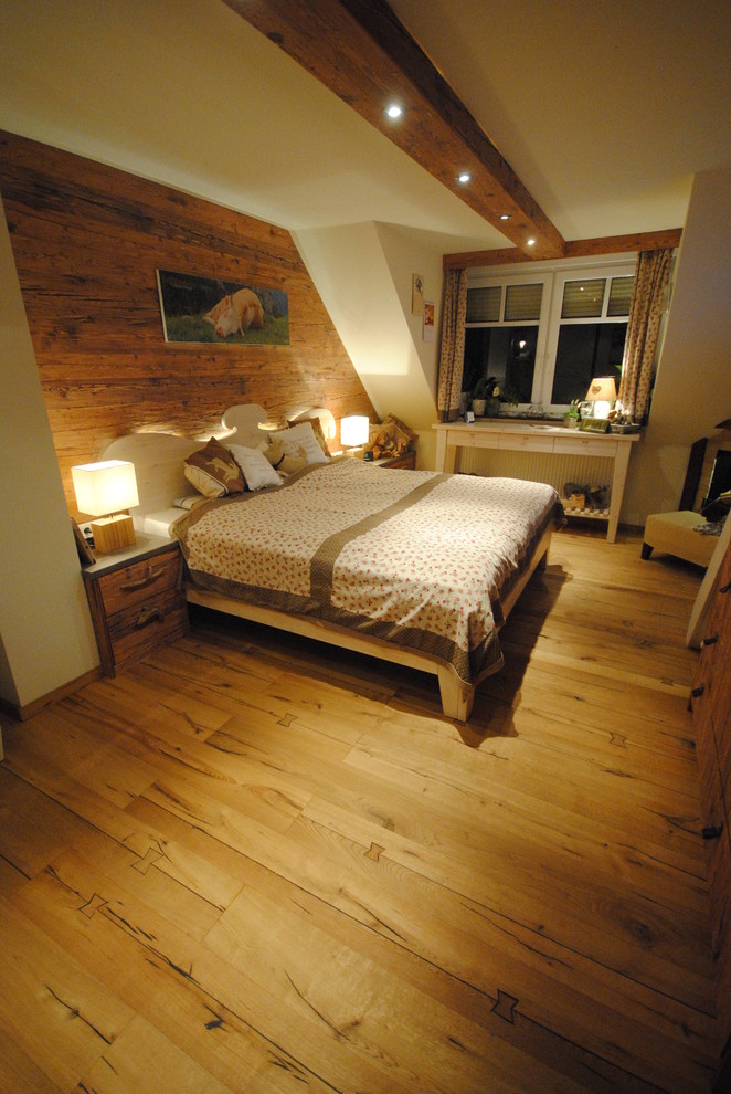 Photo of a mid-sized country master bedroom in Bremen with white walls, light hardwood floors and a corner fireplace.