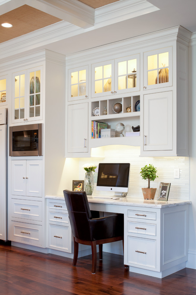 This is an example of a traditional home office in Boston with dark hardwood floors, white walls, a built-in desk and coffered.