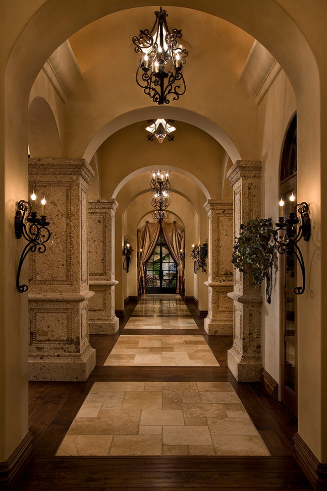 Design ideas for an expansive mediterranean foyer in Phoenix with beige walls, dark hardwood floors, a double front door, a dark wood front door and multi-coloured floor.