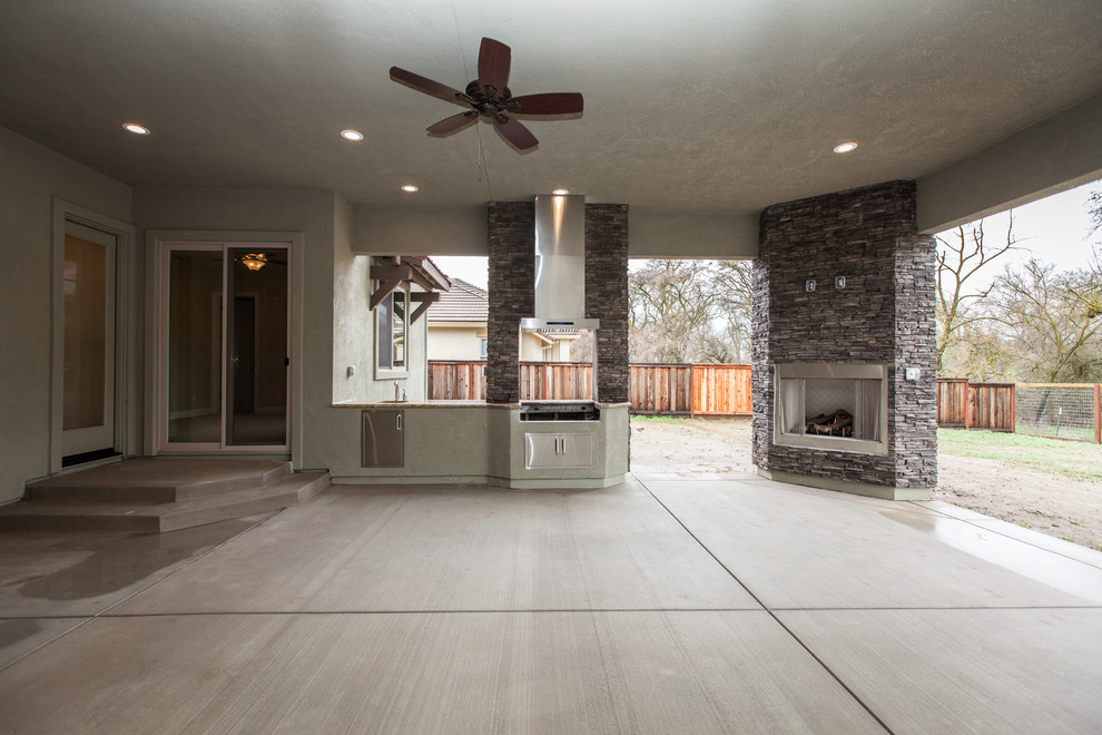 Large country backyard patio in Sacramento with an outdoor kitchen, concrete slab and a roof extension.