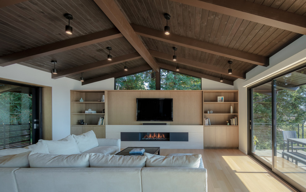 This is an example of a mid-sized contemporary loft-style living room in San Francisco with white walls, light hardwood floors, a ribbon fireplace, beige floor, a stone fireplace surround and a built-in media wall.