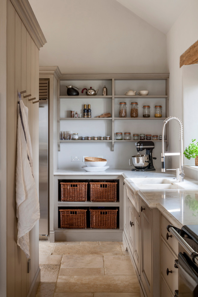 Design ideas for a large country galley open plan kitchen in Gloucestershire with a single-bowl sink, raised-panel cabinets, marble benchtops, white splashback, stone slab splashback, stainless steel appliances, limestone floors, with island and beige cabinets.