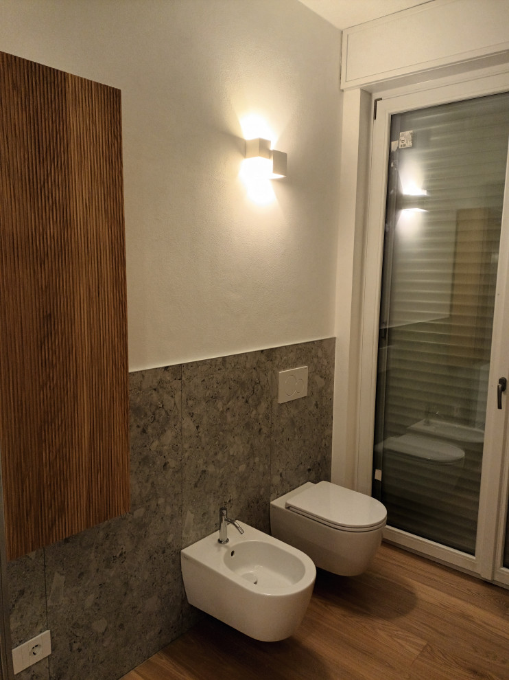 Bild på ett mellanstort funkis vit vitt badrum med dusch, med skåp i ljust trä, en kantlös dusch, en toalettstol med separat cisternkåpa, grå kakel, porslinskakel, vita väggar, mellanmörkt trägolv, ett fristående handfat, bänkskiva i kvarts och dusch med skjutdörr