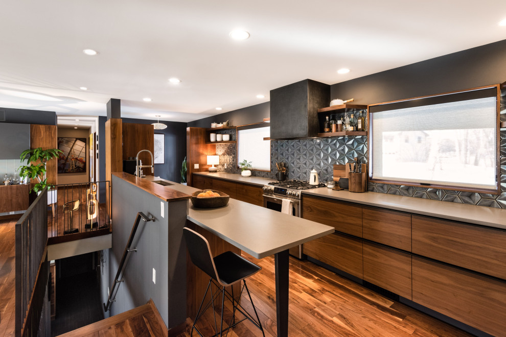 Design ideas for a small midcentury galley open plan kitchen in Minneapolis with a submerged sink, flat-panel cabinets, medium wood cabinets, engineered stone countertops, metallic splashback, stainless steel appliances, medium hardwood flooring and grey worktops.