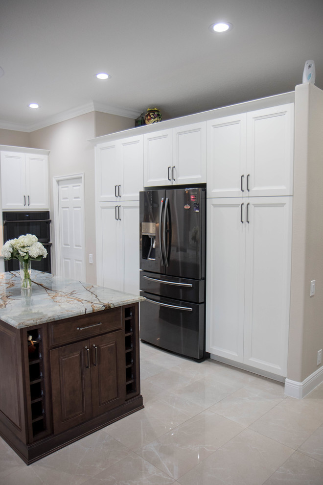 Open concept kitchen - large transitional u-shaped porcelain tile and beige floor open concept kitchen idea in Orlando with an undermount sink, recessed-panel cabinets, white cabinets, granite countertops, metallic backsplash, metal backsplash, black appliances, an island and gray countertops