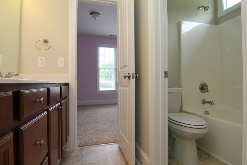 Inspiration for a mid-sized traditional bathroom in Raleigh with recessed-panel cabinets, medium wood cabinets, a drop-in tub, a one-piece toilet, beige tile, ceramic tile, beige walls and ceramic floors.