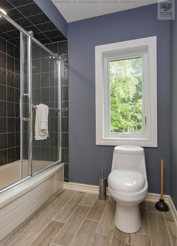 Mid-sized 3/4 bathroom in Toronto with flat-panel cabinets, beige cabinets, an alcove tub, a shower/bathtub combo, a one-piece toilet, black tile, ceramic tile, blue walls, ceramic floors, an undermount sink, tile benchtops, beige floor, a sliding shower screen, blue benchtops, a single vanity, a built-in vanity and vaulted.