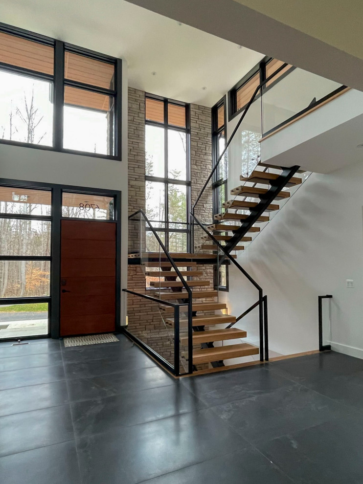 Стильный дизайн: большая лестница на больцах в стиле модернизм с деревянными ступенями и перилами из смешанных материалов - последний тренд