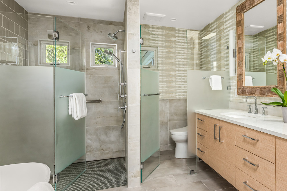 Exemple d'une grande salle de bain principale tendance en bois clair avec un placard à porte plane, une baignoire indépendante, une douche à l'italienne, un bidet, un carrelage vert, des carreaux de céramique, un mur multicolore, un sol en carrelage de porcelaine, un lavabo encastré, un plan de toilette en quartz modifié, un sol gris, une cabine de douche à porte battante, un plan de toilette blanc, des toilettes cachées, meuble double vasque, meuble-lavabo suspendu et du papier peint.