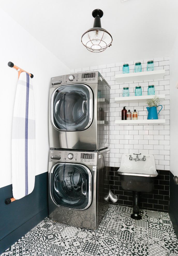 Transitional dedicated laundry room in Los Angeles with open cabinets, white cabinets, multi-coloured walls, a stacked washer and dryer and multi-coloured floor.