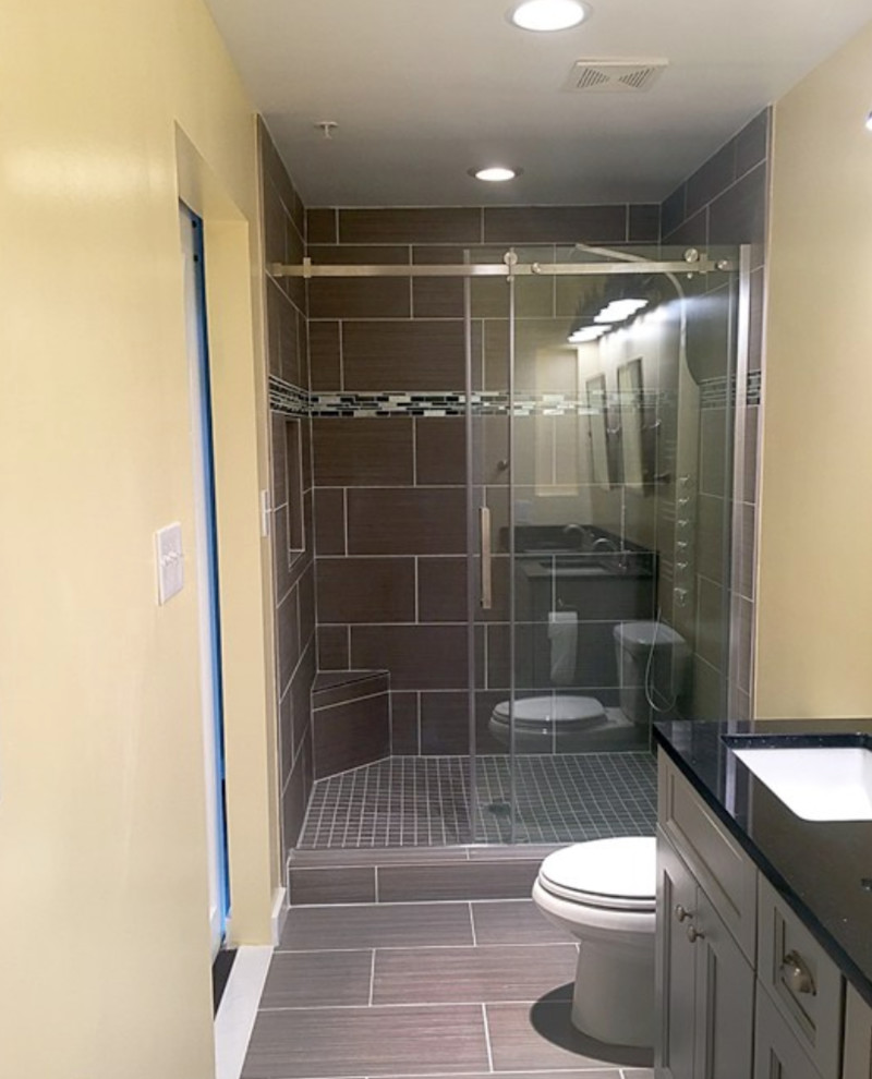 Design ideas for a mid-sized transitional 3/4 bathroom in DC Metro with recessed-panel cabinets, grey cabinets, an alcove shower, a two-piece toilet, brown tile, porcelain tile, yellow walls, porcelain floors, an undermount sink, engineered quartz benchtops, brown floor, a sliding shower screen and black benchtops.