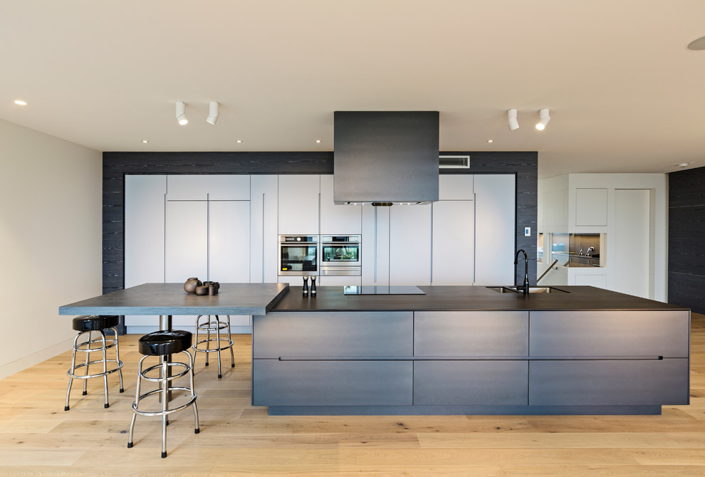 Inspiration for a large contemporary galley eat-in kitchen in Melbourne with a double-bowl sink, flat-panel cabinets, dark wood cabinets, stainless steel appliances, light hardwood floors, with island, quartz benchtops and beige floor.