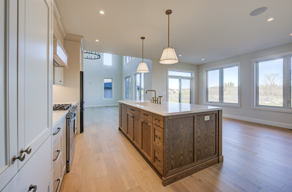 Open concept kitchen - mid-sized transitional single-wall light wood floor open concept kitchen idea with an undermount sink, shaker cabinets, quartz countertops, white backsplash, quartz backsplash, stainless steel appliances, an island, white countertops and medium tone wood cabinets