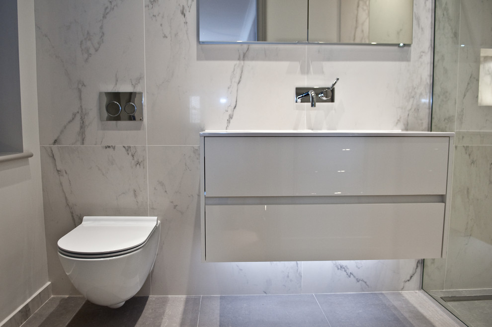 Small contemporary master bathroom in London with white cabinets, an open shower, a one-piece toilet, gray tile, stone tile, grey walls and a wall-mount sink.