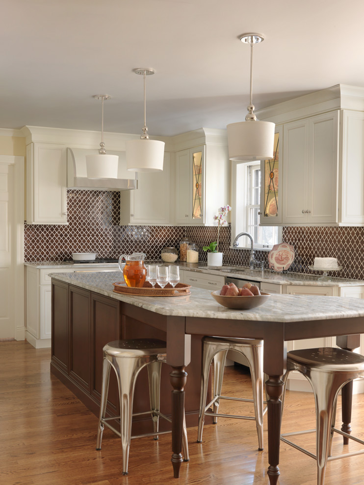 Inspiration for a transitional l-shaped medium tone wood floor kitchen remodel in St Louis with granite countertops, brown backsplash, an island, shaker cabinets and beige cabinets