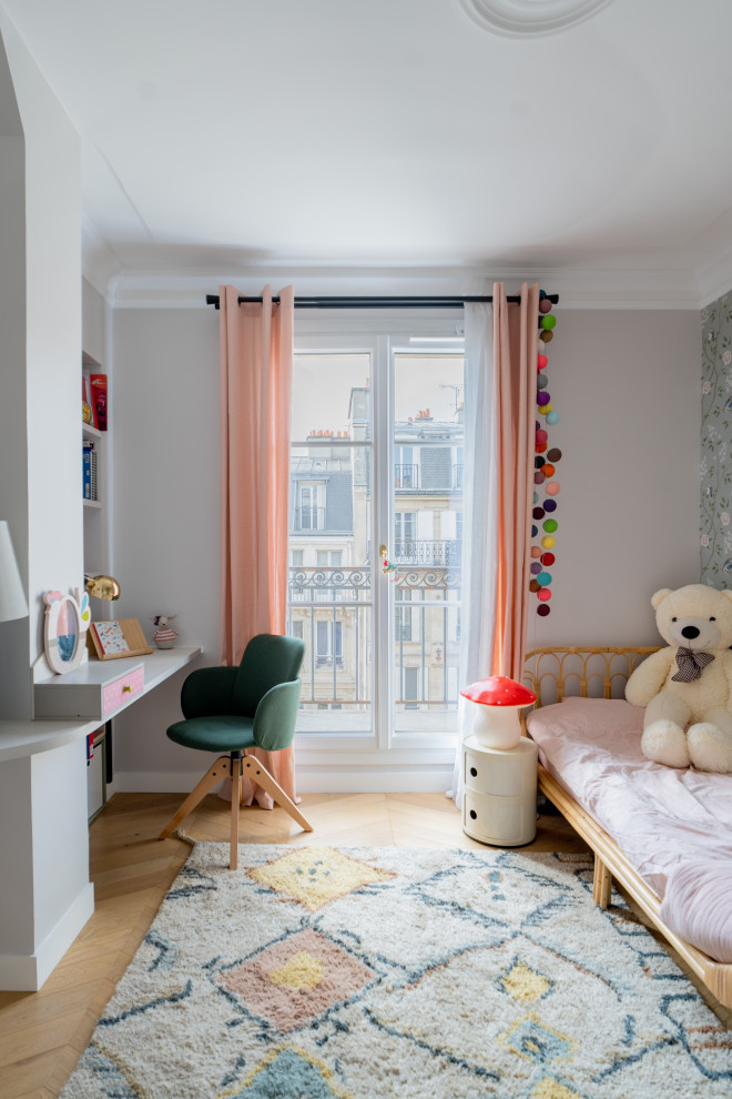 This is an example of a large contemporary gender-neutral kids' bedroom for kids 4-10 years old in Paris with light hardwood floors, brown floor and wallpaper.