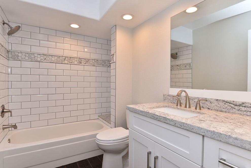Example of a mid-sized transitional master white tile dark wood floor alcove bathtub design in Phoenix with shaker cabinets, white cabinets, granite countertops, an undermount sink, a one-piece toilet and white walls