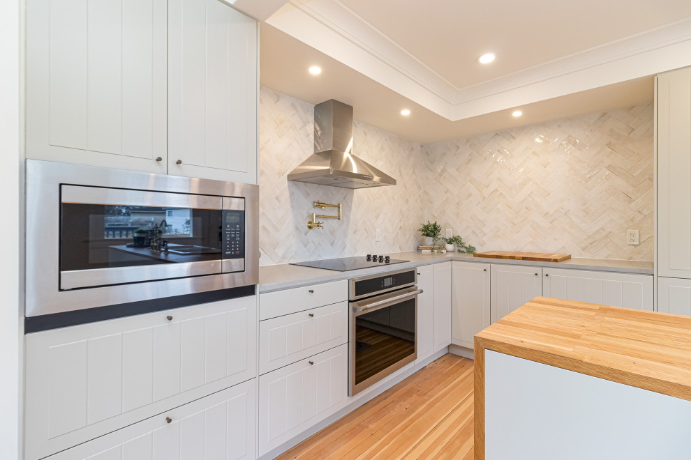 Eat-in kitchen - mid-sized transitional l-shaped medium tone wood floor, brown floor and coffered ceiling eat-in kitchen idea with a farmhouse sink, raised-panel cabinets, gray cabinets, wood countertops, beige backsplash, ceramic backsplash, stainless steel appliances, an island and brown countertops