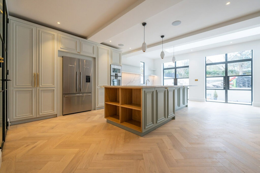 Idéer för avskilda, stora funkis linjära brunt kök, med en nedsänkt diskho, luckor med profilerade fronter, vita skåp, bänkskiva i rostfritt stål, vitt stänkskydd, stänkskydd i trä, vita vitvaror, vinylgolv, en köksö och brunt golv