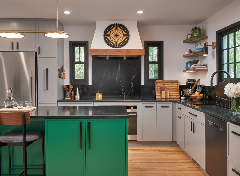 Mid-sized transitional l-shaped kitchen in Minneapolis with an undermount sink, shaker cabinets, grey cabinets, soapstone benchtops, black splashback, stone slab splashback, stainless steel appliances, light hardwood floors, with island and black benchtop.