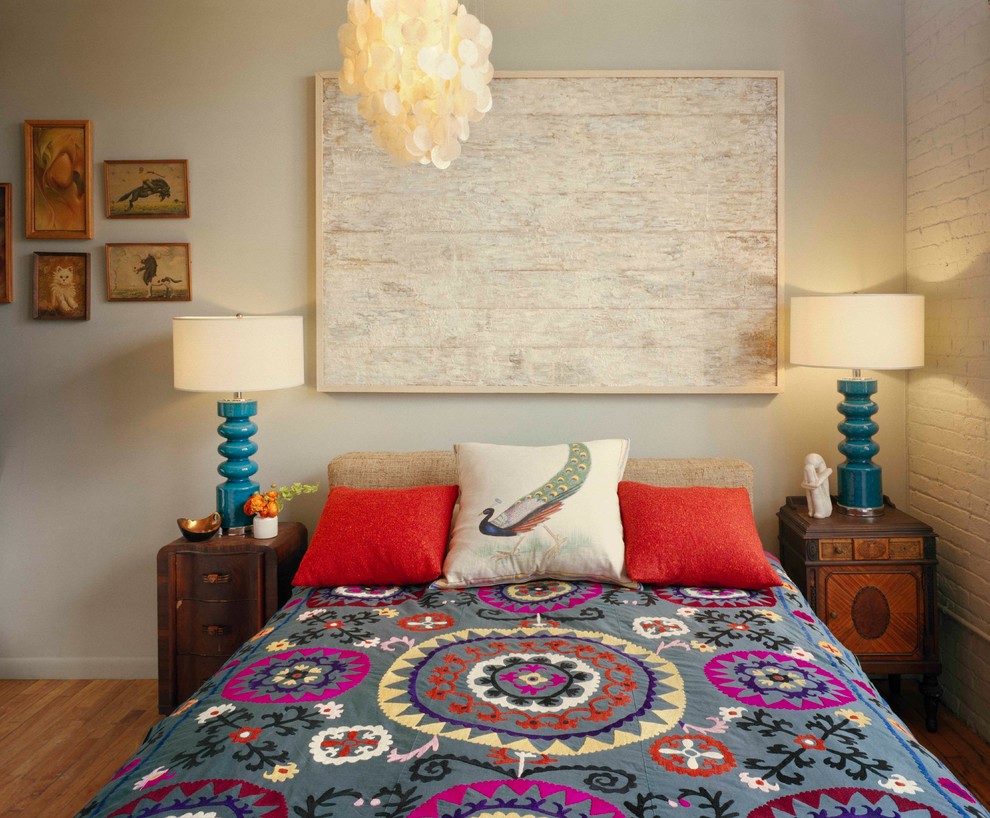 This is an example of an eclectic bedroom in New York with beige walls and medium hardwood floors.
