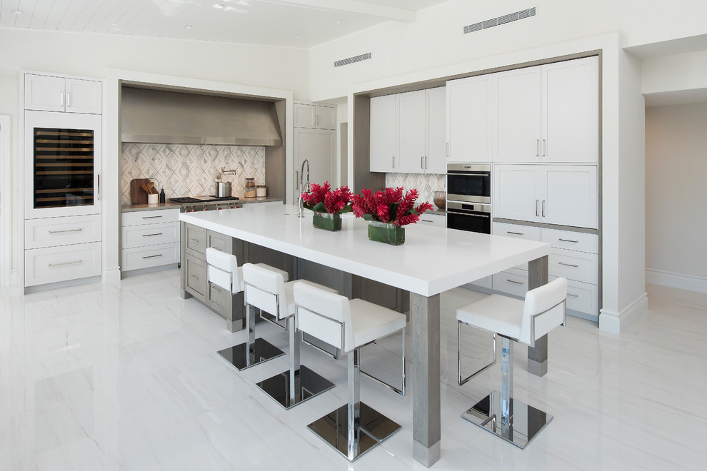 Kitchen - transitional l-shaped white floor kitchen idea in Miami with shaker cabinets, white cabinets, gray backsplash, an island and white countertops